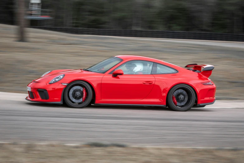 a red car driving along a track near a street