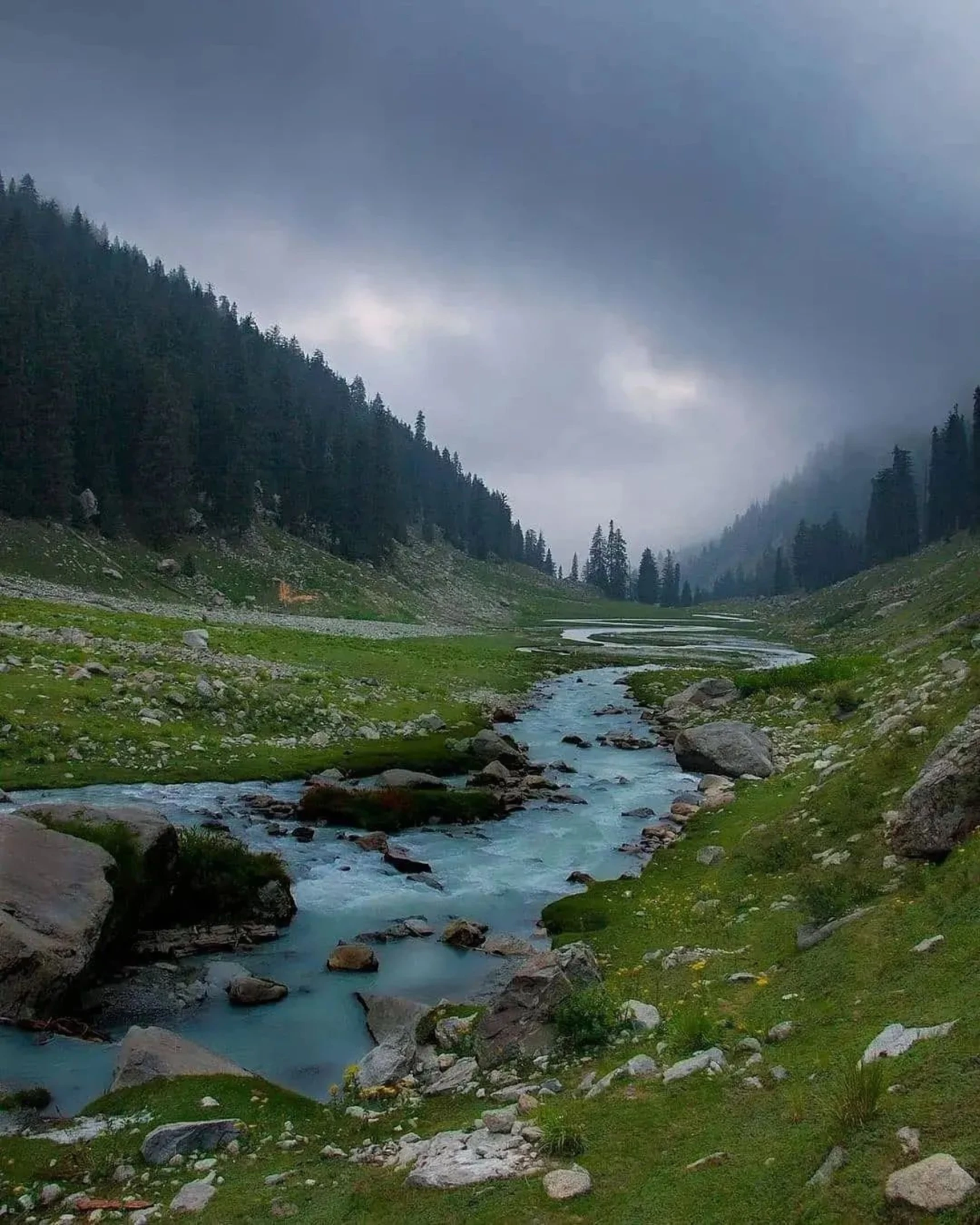 a stream running in the mountains next to rocks