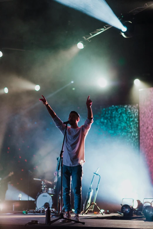 man on stage with his arms up in the air