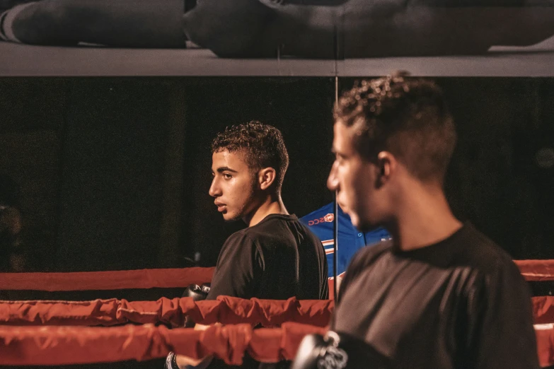 two young men standing in the ring in black and orange