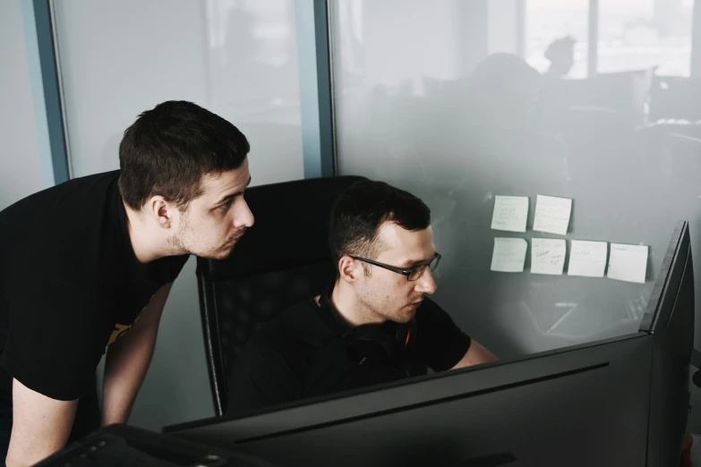 two guys are looking at a computer monitor