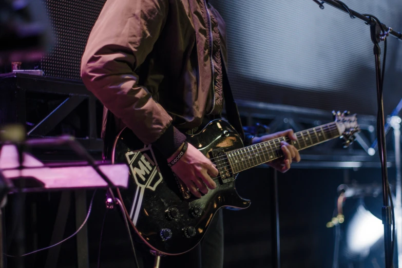 a man playing guitar on stage next to a microphone