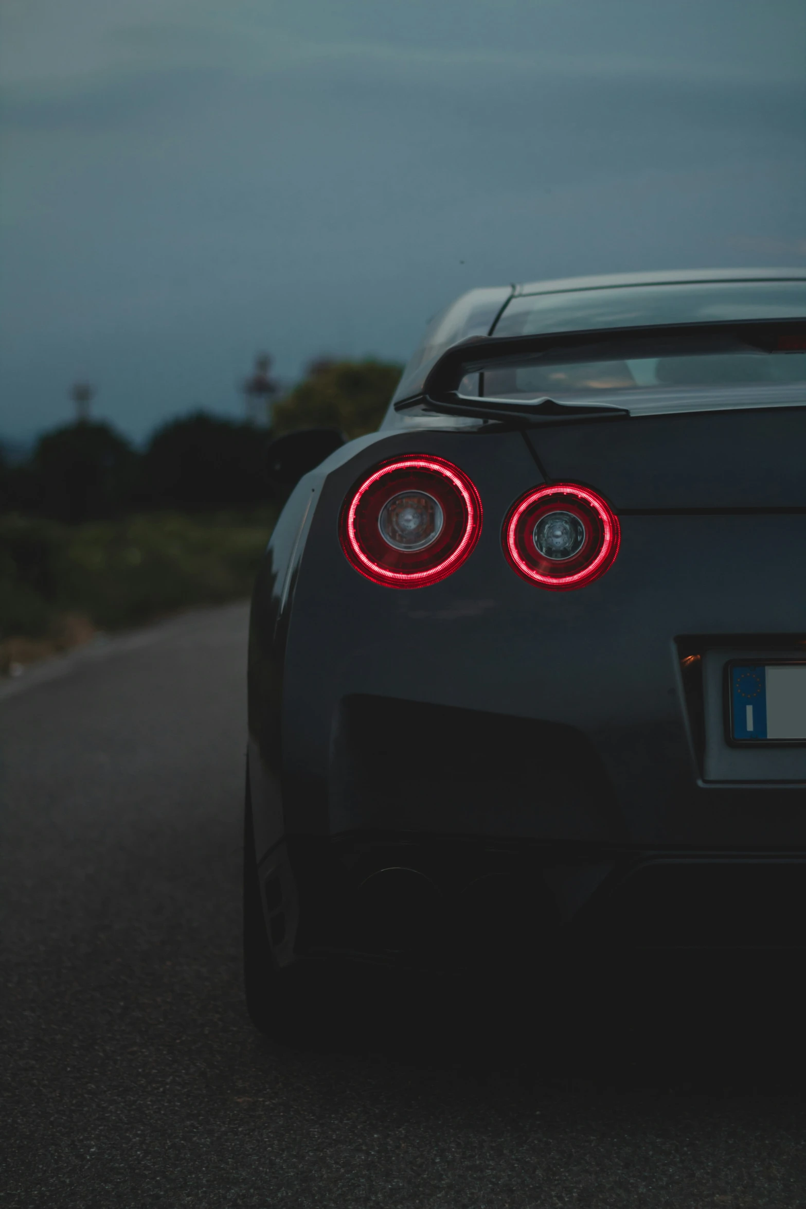 a black sports car parked on the road with its tail lights turned red