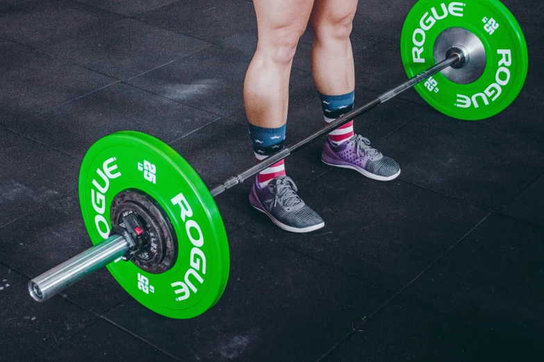 a person standing next to a green weight bar