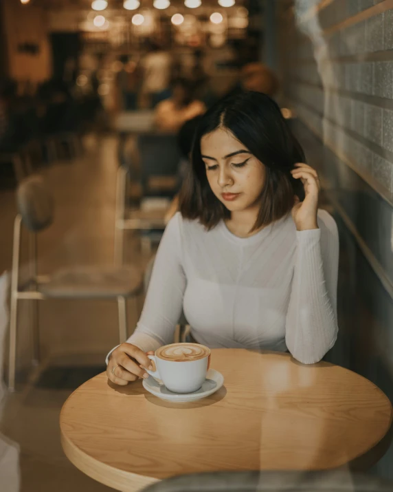 a woman sitting at a table with her cup of coffee