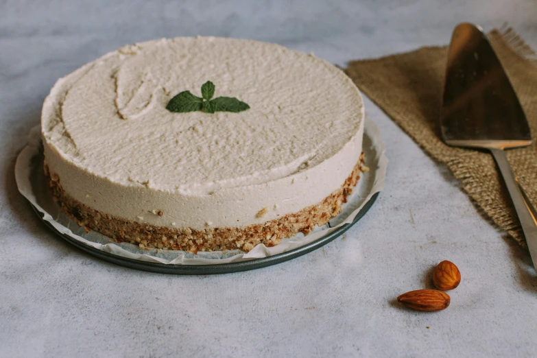 a white frosted cake with green leaves and a spoon sitting next to it