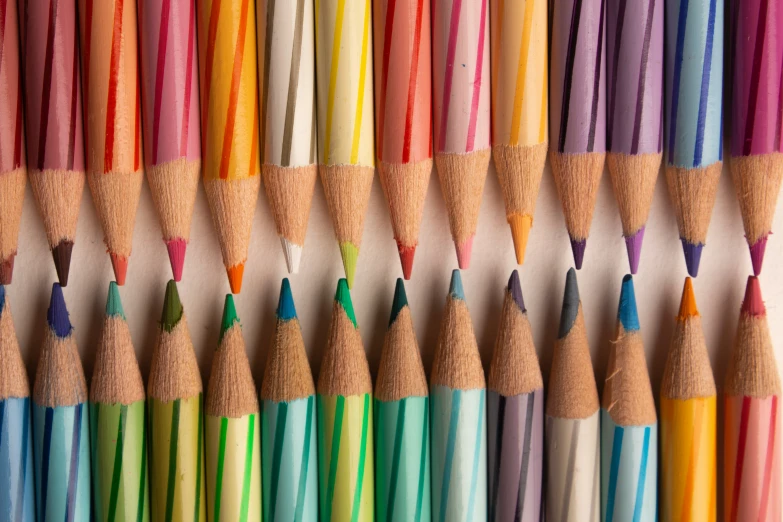 the many colored pencils are lined up in rows