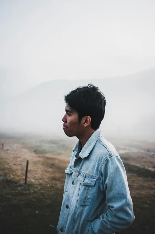 a man standing in the grass with his hands in his pockets