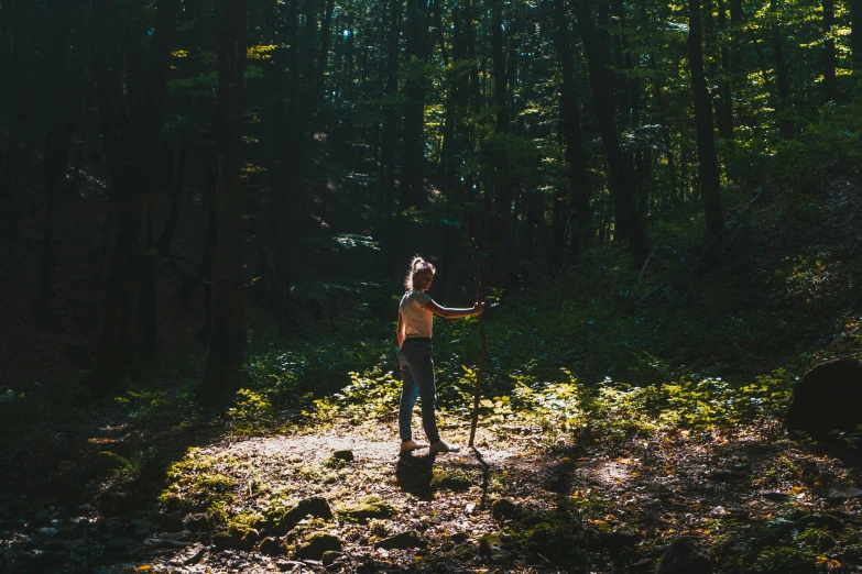 a woman stands on a trail with one hand raised above her head