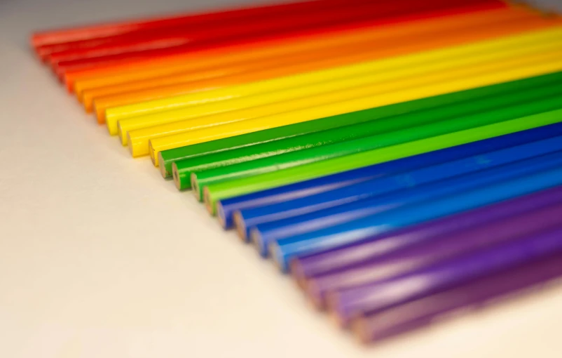 rainbow colored pencils that are lined up on a white table