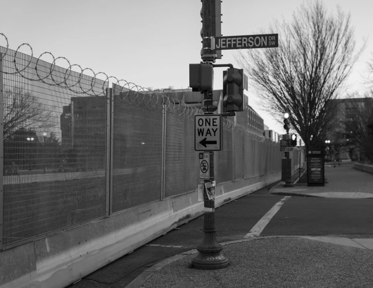 a one way street signs is posted near the fence