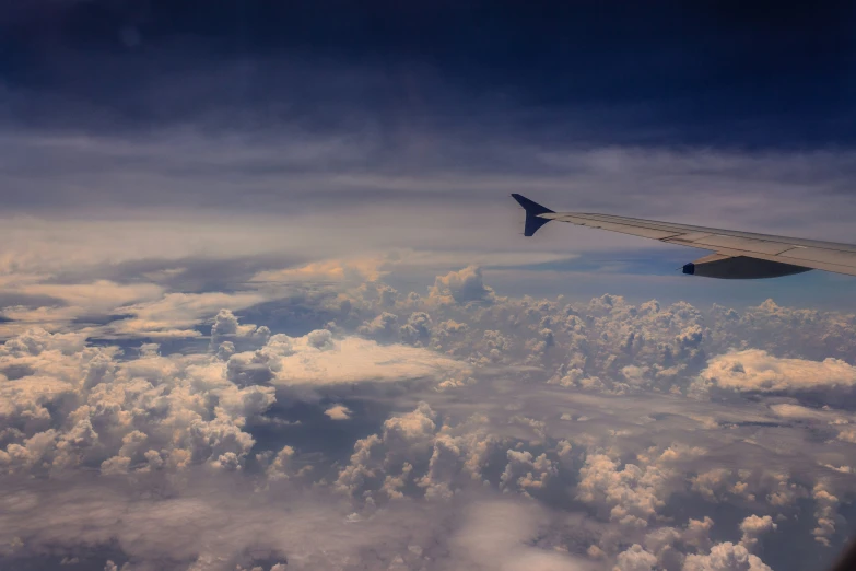 a wing on a airplane flying above the clouds