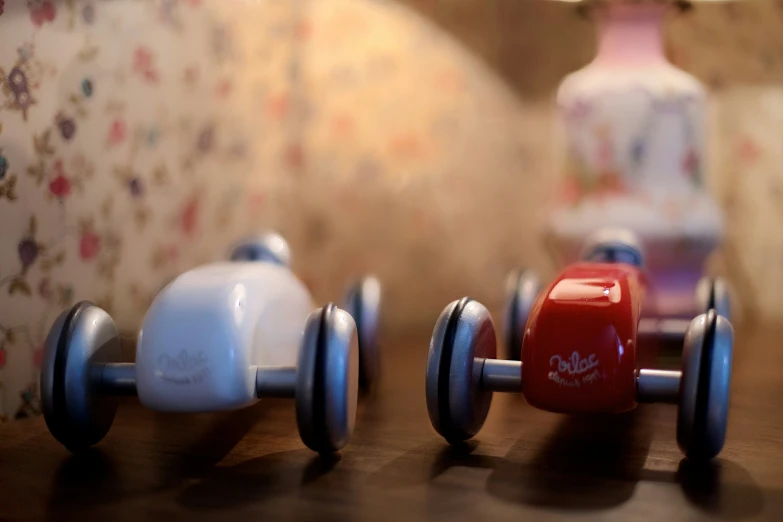 two plastic toy cars sitting on top of a wooden table