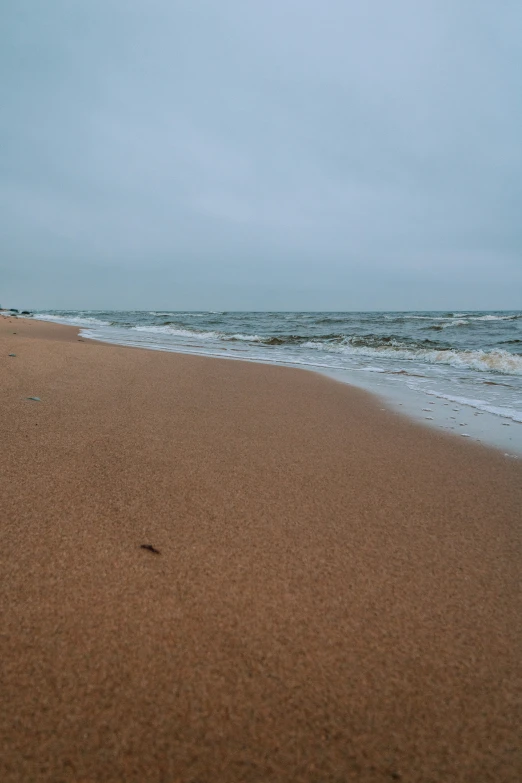 a person on the beach walking with their surfboard