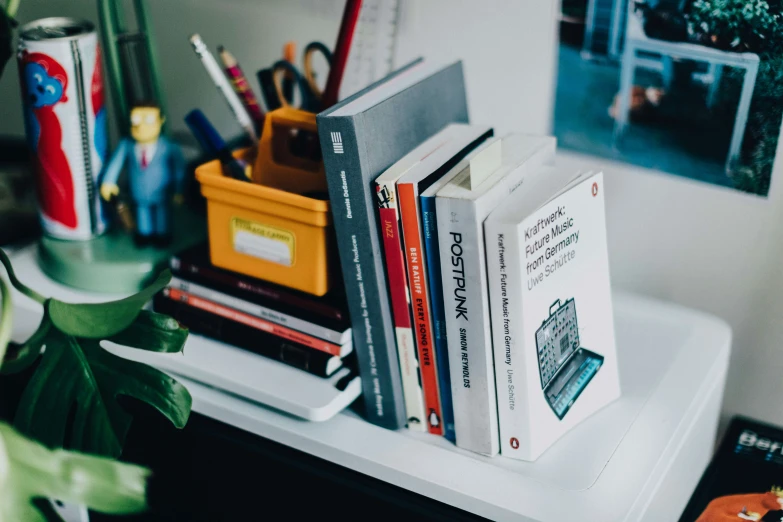 the books are on top of each other by the desk