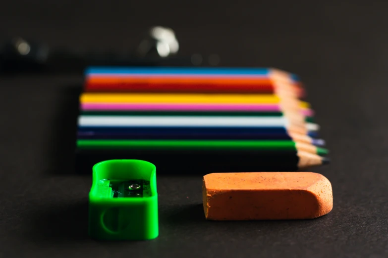 a pair of green rubber grips stand next to the other colorful pencils