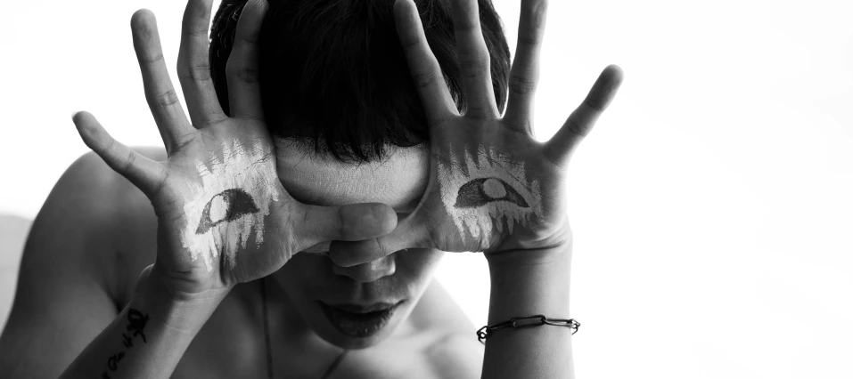 a black and white po of a woman with her hands covering her eyes