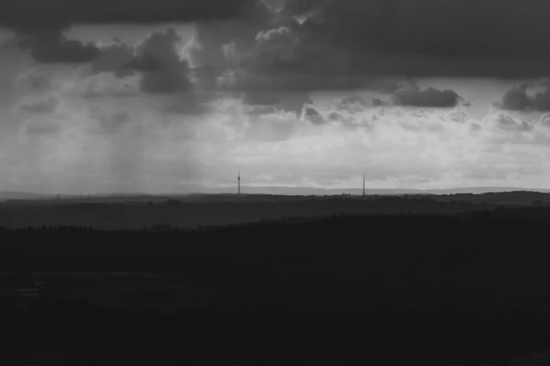 a field with trees and dark clouds in the sky