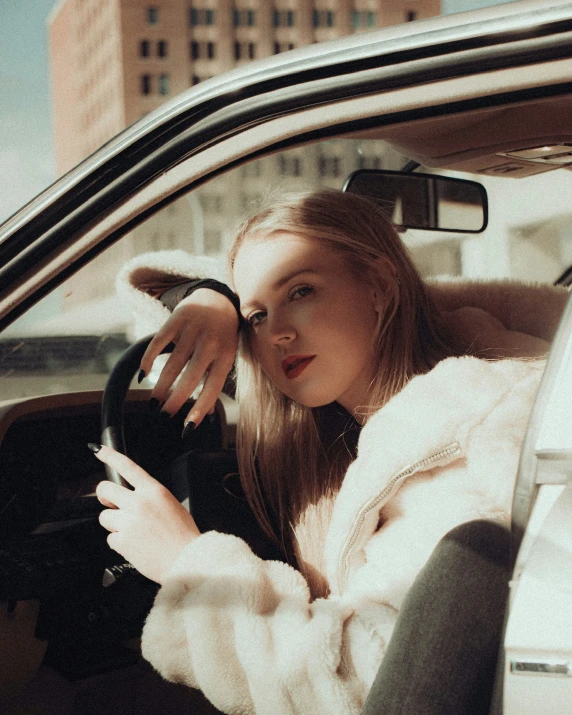 a woman in a fur coat is driving her car