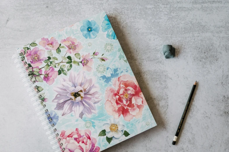 a notebook sitting on a table next to a pencil and pen