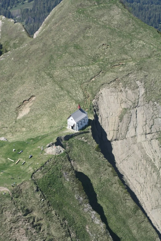 the house sits on top of a cliff and overlooks another large hill
