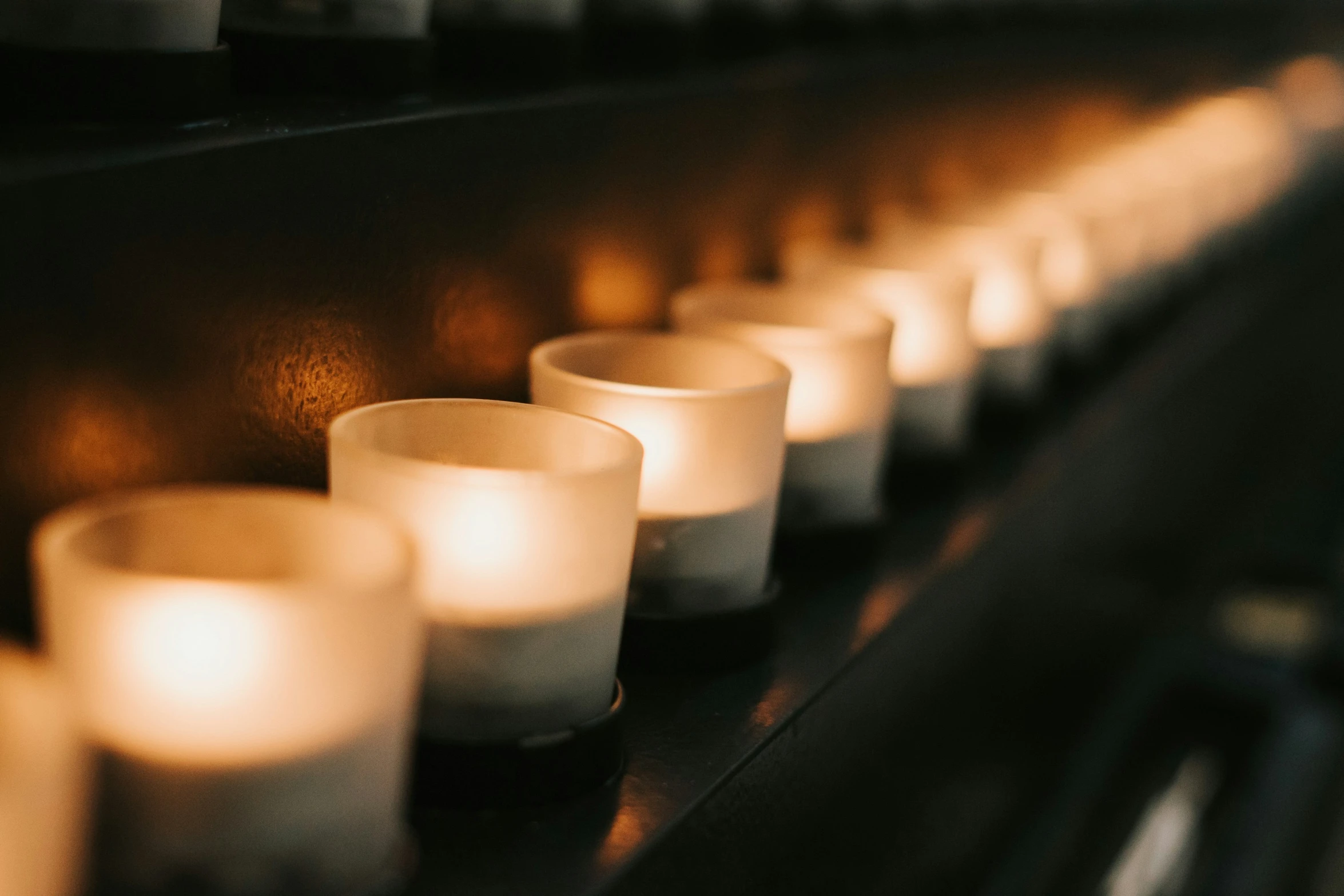 lit candles on the shelf of a church