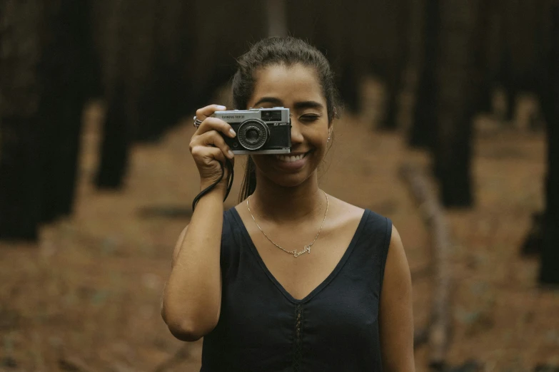 a woman standing in the forest taking a selfie