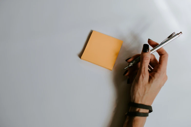 a person holds a pen and rests on top of an empty notebook