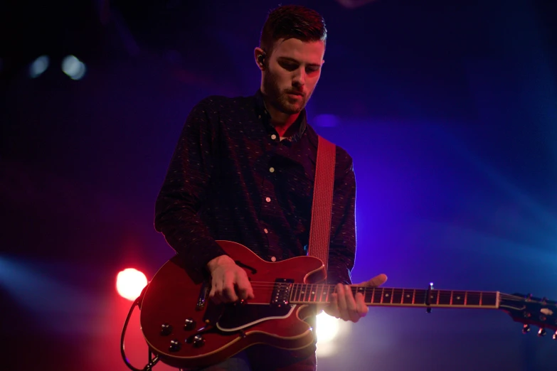 a man plays the guitar while wearing headphones on stage