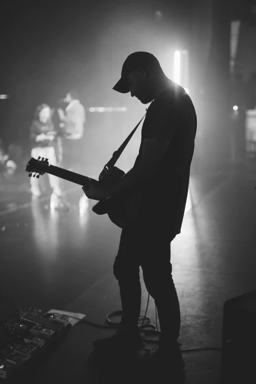 a man playing a guitar with a microphone and other musicians in the background