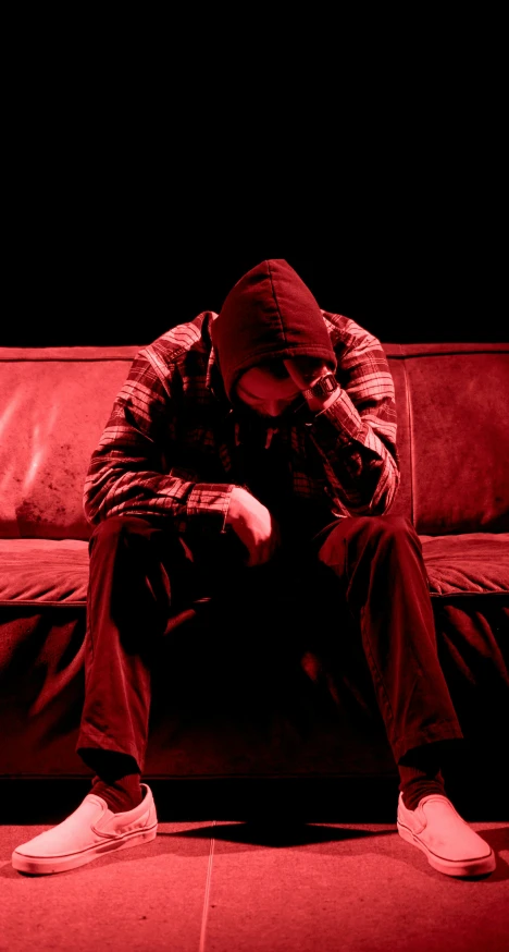 a man in a hoodie and cap is sitting on the couch