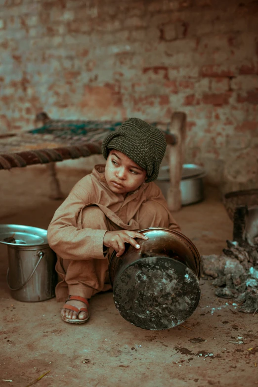 a young child sitting on the floor next to a bucket