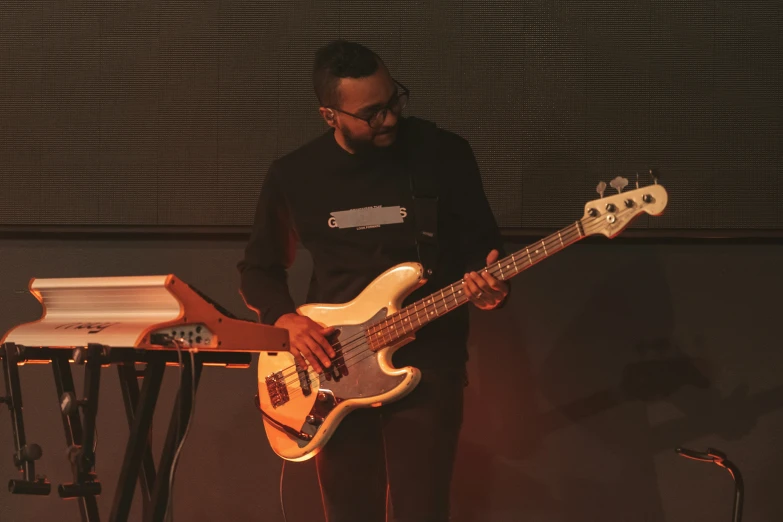 a man in glasses playing on a white electric bass guitar