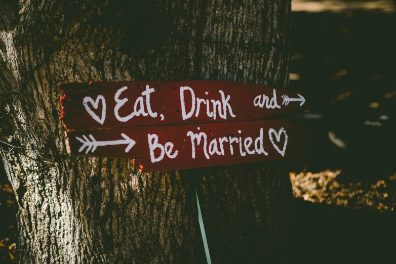 a sign on the trunk of a tree that says eat drink and be married