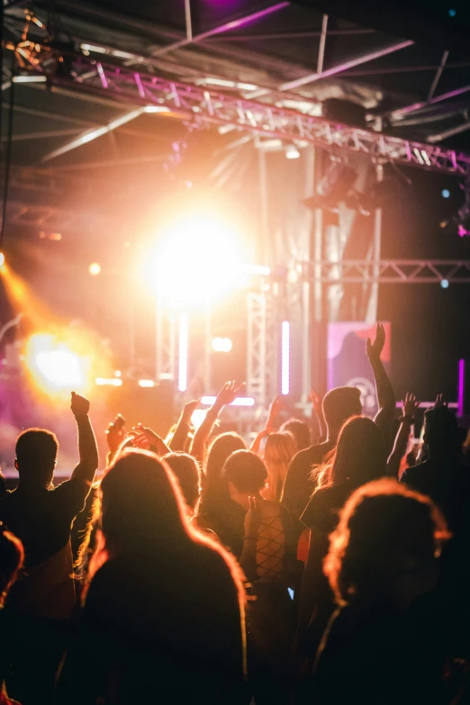 a crowd at a music festival with their hands up in the air