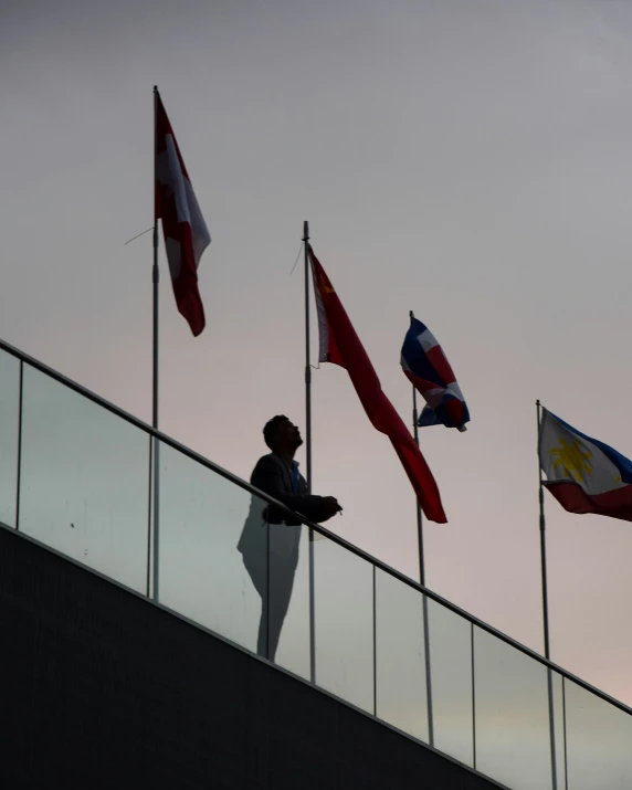 a man sitting on a glass wall looking down on the ground