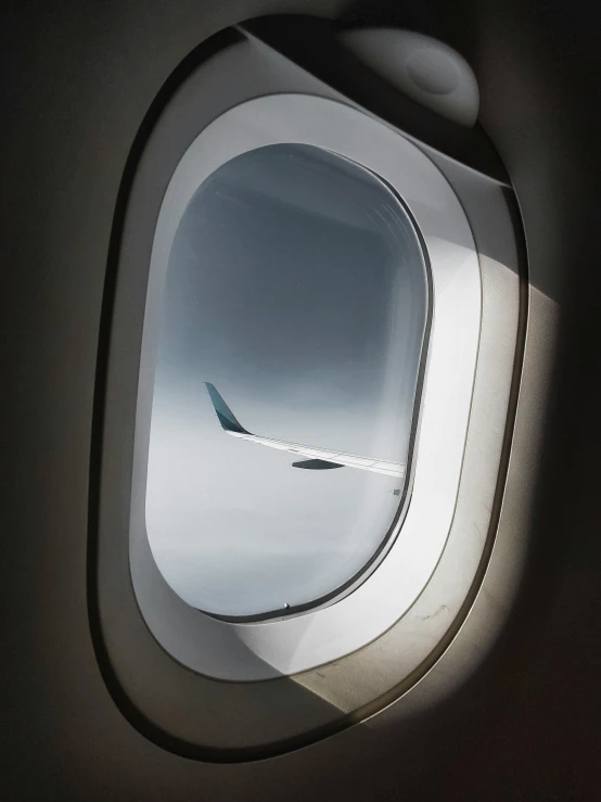 an airplane window with the wing visible looking upward