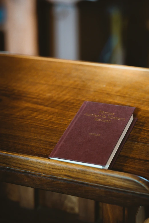 a maroon colored book laying on top of a wooden bench