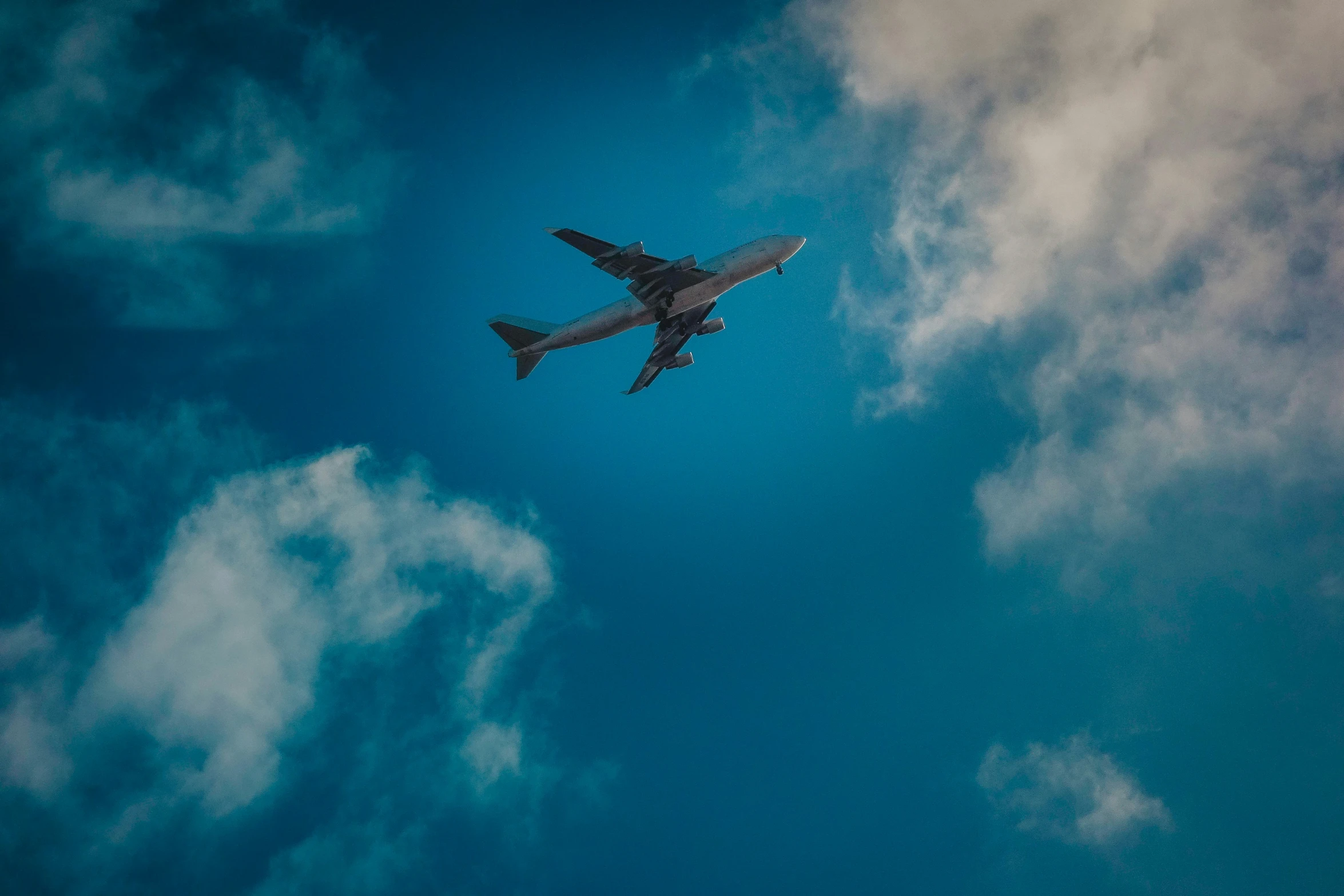 a large plane flying through the blue cloudy sky