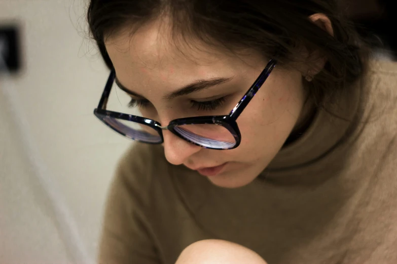 a woman in glasses looking at her cell phone