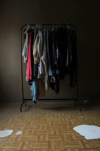 a clothes rack in an empty room with clothing hanging from it