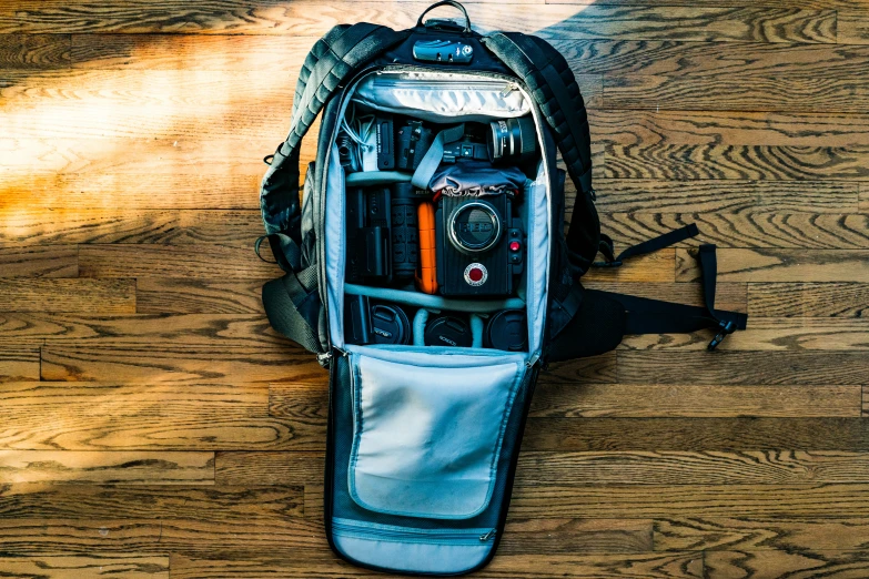 a backpack filled with assorted items sitting on top of a wooden floor