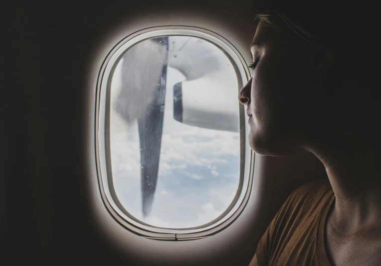 a man looking out an airplane window at a wing