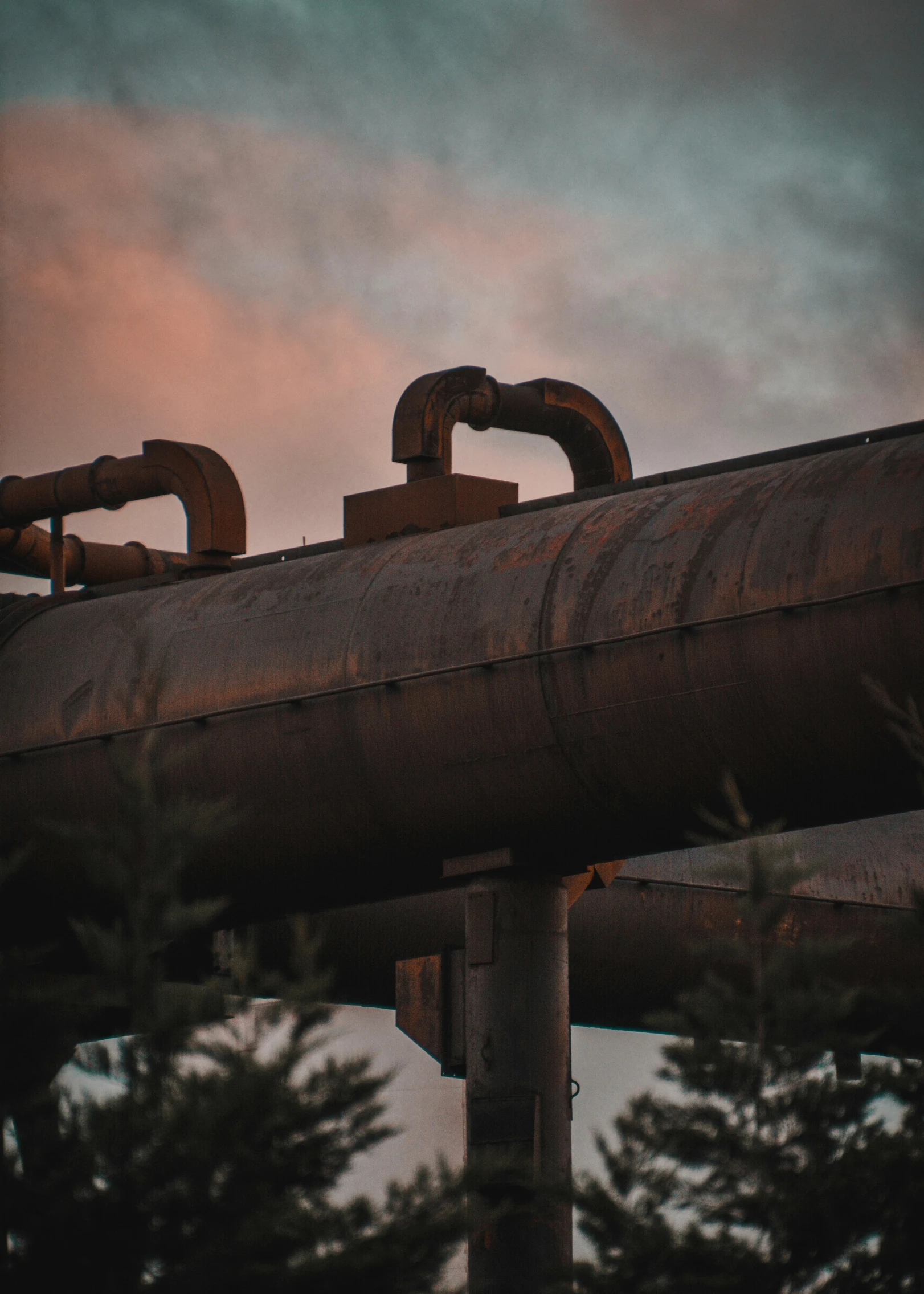 three rusty pipes hang from the top of a pipe