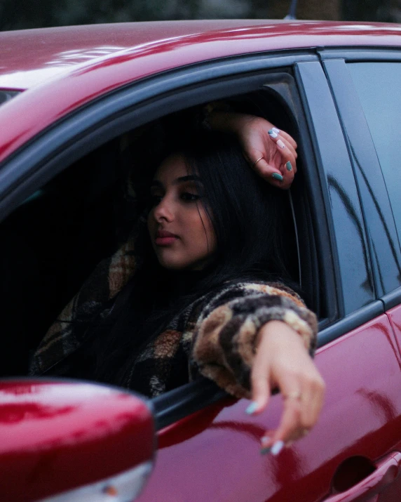 a woman is sitting in the car pointing out the window