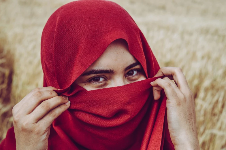 the woman is covering her face with a red scarf