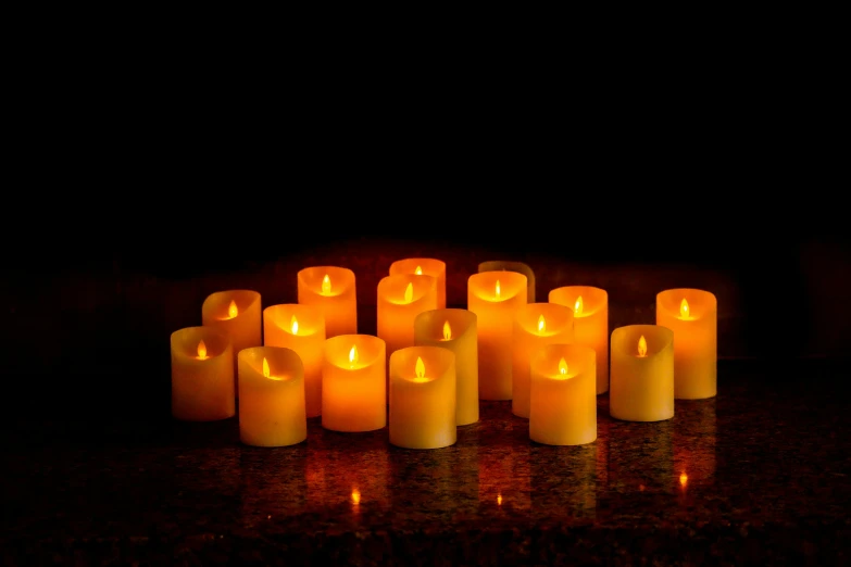 many lit candles are arranged in the shape of squares