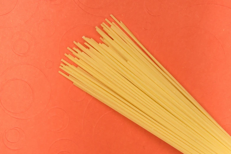 a bunch of pasta sitting on a bright orange background