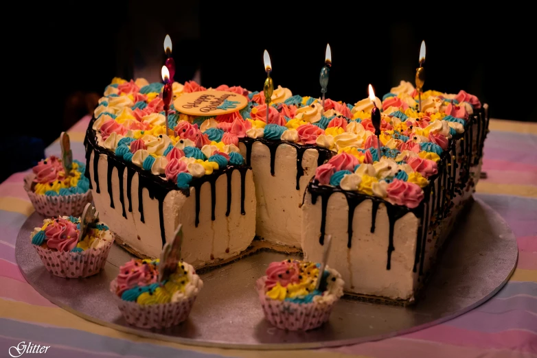 a cake sitting on top of a metal tray topped with lots of cupcakes