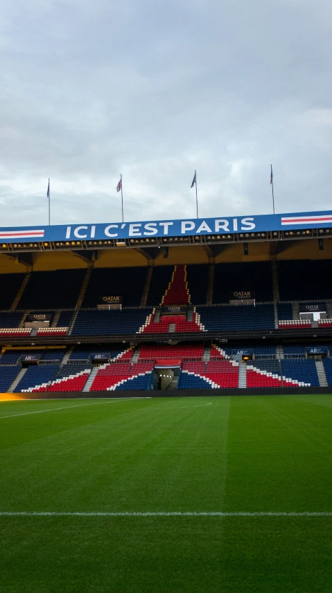 a field in front of the big stadium, where people are waiting for a match